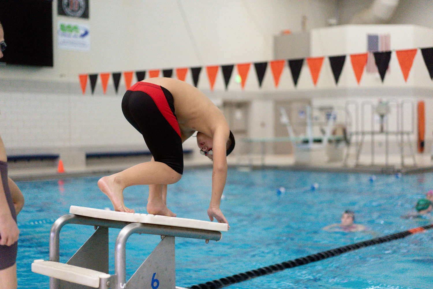 Young swimmer at starting block preparing to dive