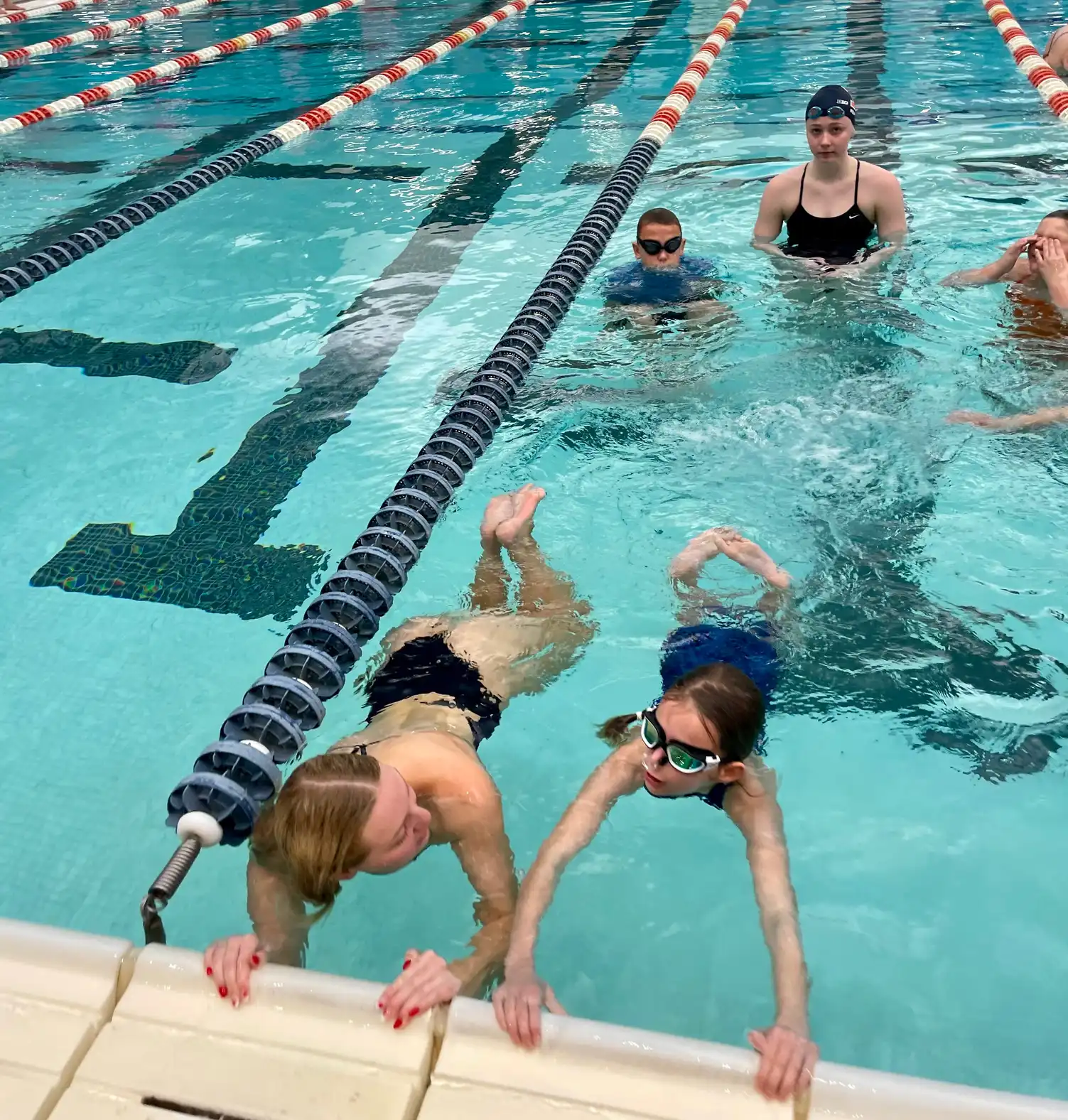 Young swimmers learning at pool edge during lesson